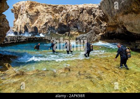 La Valette de Malte 16 juin 2019 : beaucoup de plongeurs de l'équipement entrent dans l'eau pure bleue d'un petit canyon par une journée ensoleillée. Le canyon est Banque D'Images