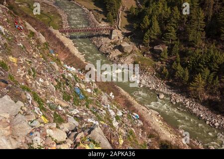 Une pente raide qui descend vers la rivière Baspa jonchée de déchets en plastique jetés par les touristes dans le village de Chitkul dans l'Himachal Pradesh, en Inde. Banque D'Images