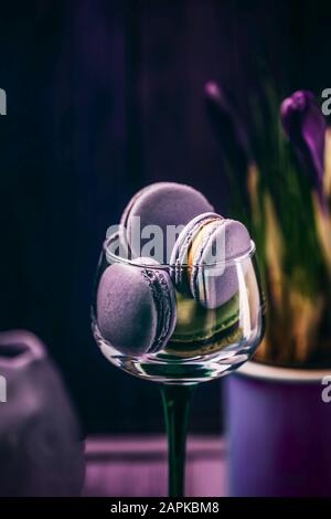 Exquise macarons ou macarons de lavande violette française dans un verre et crocuses fleurs sur fond sombre Banque D'Images