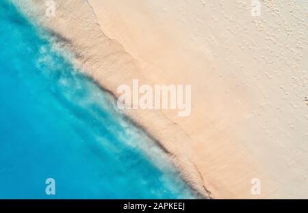 Vue aérienne sur la mer bleu clair avec vagues et plage de sable vide Banque D'Images