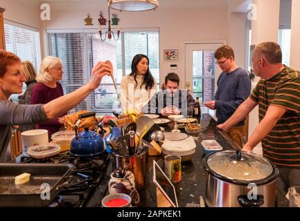 La famille s'est rassemblée autour de l'île du centre de cuisine pour un dîner de Thanksgiving de style buffet Banque D'Images