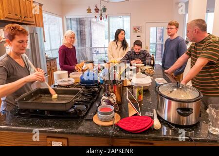 La famille s'est rassemblée autour de l'île du centre de cuisine pour un dîner de Thanksgiving de style buffet Banque D'Images