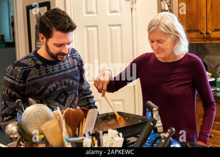 La famille s'est rassemblée autour de l'île du centre de cuisine pour un dîner de Thanksgiving de style buffet Banque D'Images