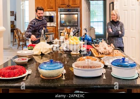 La famille s'est rassemblée autour de l'île du centre de cuisine pour un dîner de Thanksgiving de style buffet Banque D'Images