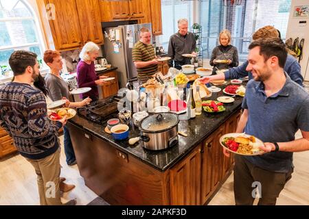 La famille s'est rassemblée autour de l'île du centre de cuisine pour un dîner de Thanksgiving de style buffet Banque D'Images