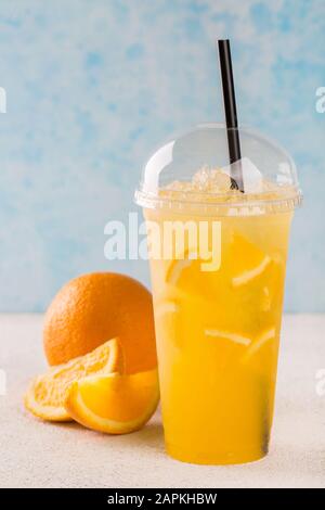 Limonade orange dans un verre en plastique. Banque D'Images