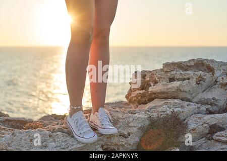 Jambes de la jeune femme, debout sur une falaise au bord de la mer Banque D'Images