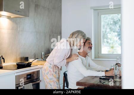 Couple affectueux à la table dans la cuisine à la maison Banque D'Images