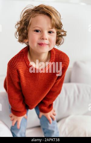 Portrait de la fille souriante debout sur le canapé à la maison Banque D'Images