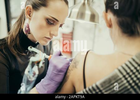 tatouage féminin bras supérieur du client féminin Banque D'Images