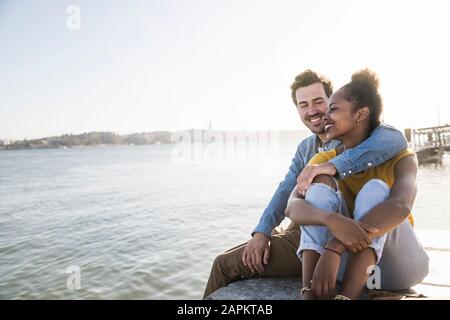 Happy young couple sitting on pier au Waterfront, Lisbonne, Portugal Banque D'Images