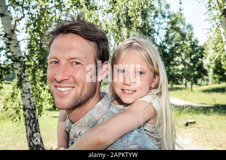 Portrait of happy father carrying daughter piggyback Banque D'Images