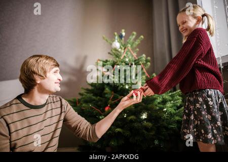 Blonde fille avec son père décorant arbre de Noël Banque D'Images
