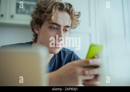 Jeune homme utilisant un smartphone à la maison Banque D'Images