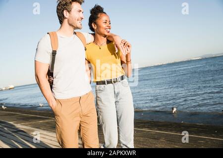 Un jeune couple heureux qui marche au bord de l'eau, Lisbonne, Portugal Banque D'Images