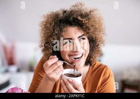 Portrait d'une heureuse femme qui mange du chocolat étalé à la maison Banque D'Images