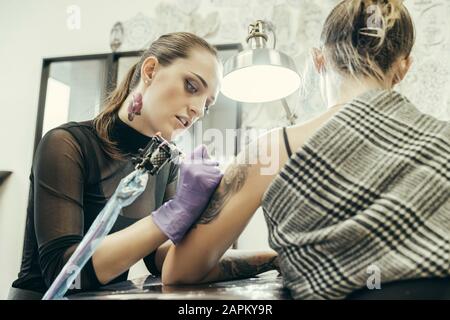 tatouage féminin bras supérieur du client féminin Banque D'Images