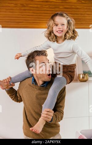Joyeux père portant sa fille sur les épaules à la maison Banque D'Images