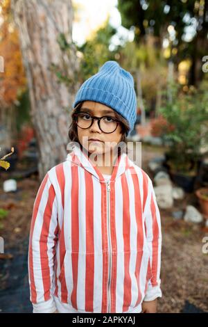 Portrait d'un petit garçon sérieux portant un chapeau et des lunettes de laine bleus Banque D'Images