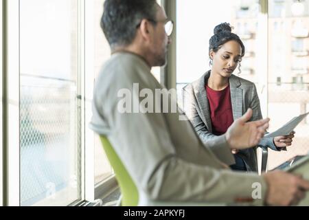 Mature businessman talking to young businesswoman in office Banque D'Images