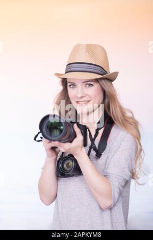 Portrait de jeune femme souriante comparant deux appareils photo différents Banque D'Images