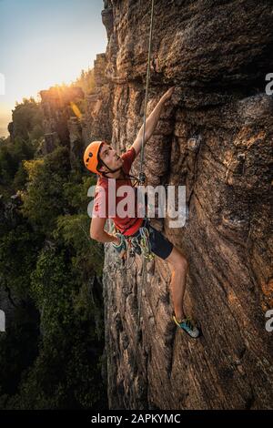 Homme grimpant à Batt rock au coucher du soleil, Baden-Baden, Allemagne Banque D'Images