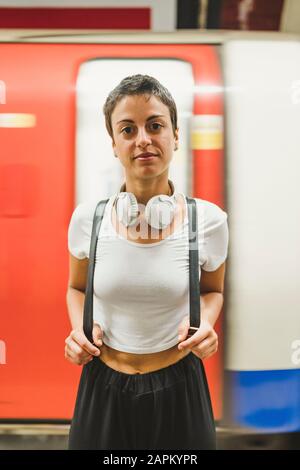 Portrait d'une femme avec sac à dos devant un train souterrain, Londres, Royaume-Uni Banque D'Images