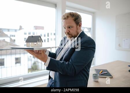 Businessman holding model house in office Banque D'Images