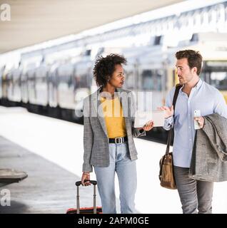 Jeune homme d'affaires et femme d'affaires utilisant un comprimé ensemble à la gare Banque D'Images