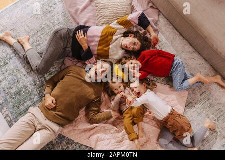 Famille heureuse avec trois filles allongé sur des couvertures à la maison Banque D'Images