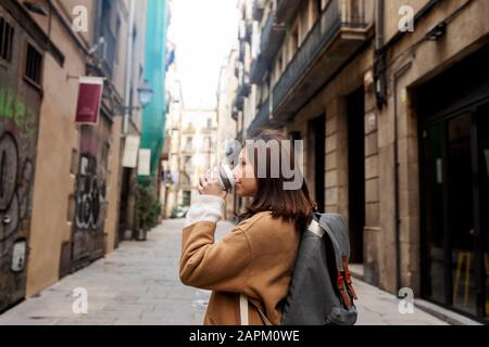 Jeune femme avec café à emporter dans la ville, Barcelone, Espagne Banque D'Images