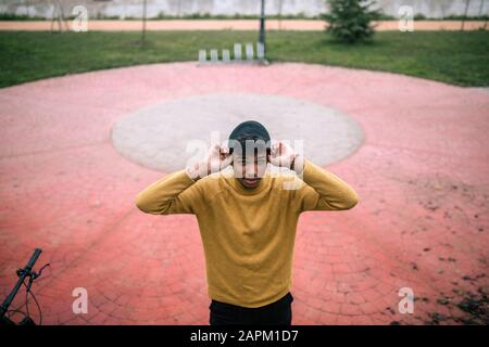 Portrait d'un jeune homme confiant en plein air mettant sur le bonnet Banque D'Images