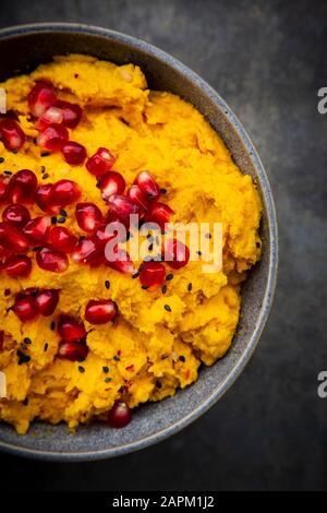 Bol de houmous de citrouille avec graines de sésame noir et de grenade Banque D'Images