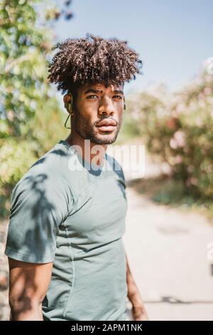 Portrait de jeune homme portant un t-shirt vert dans un parc Banque D'Images