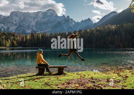 Couple à Laghi di Fusine, femme sautant de banc, Friuli Venezia Giulia, Italie Banque D'Images