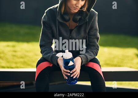 Femme prenant une pause après l'entraînement, tenant la bouteille de boisson Banque D'Images