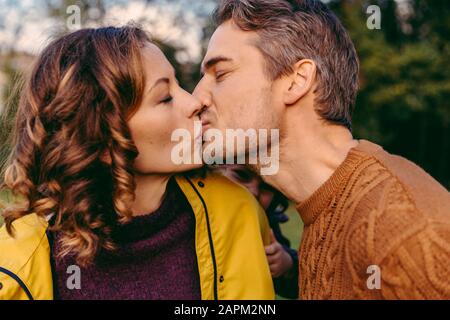 Couple embrassant dehors en automne regardé par sa fille Banque D'Images