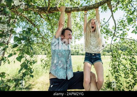 Père et fille accrochés sur une branche d'un bouleau Banque D'Images