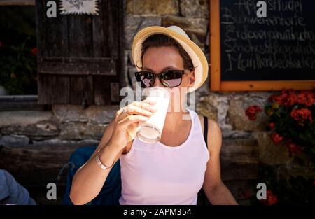 Femme qui aime un verre de babeurre dans une cabane de montagne, la vallée du Passeier, Tyrol du Sud, Italie Banque D'Images