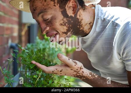 Jeune homme avec vitiligo avec un chapeau qui frayent les plantes Banque D'Images