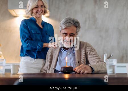 Couple d'âge mûr célébrant l'anniversaire avec gâteau dans la cuisine à la maison Banque D'Images