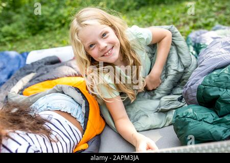 Petite fille posée sur le sac de couchage, regardant l'appareil photo Banque D'Images