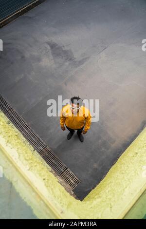 Homme d'âge mûr portant une veste jaune et debout sur la voie Banque D'Images