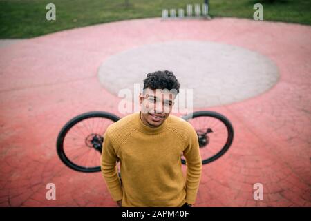 Portrait de jeune homme souriant avec vélo à l'extérieur Banque D'Images