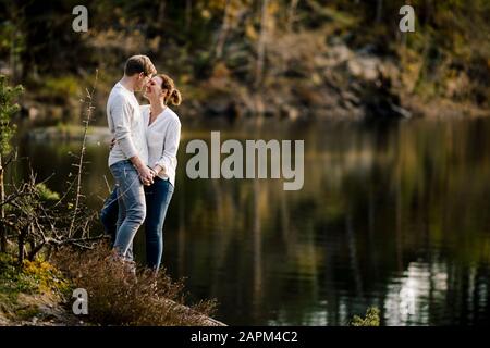 Couple affectueux debout sur un rocher au bord du lac, Forstsee, Carinthie, Autriche Banque D'Images