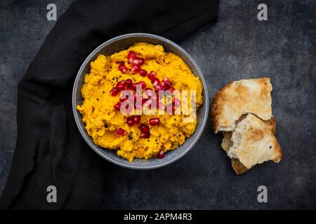 Pain pita et bol de houmous de citrouille avec graines de sésame noir et de grenade Banque D'Images