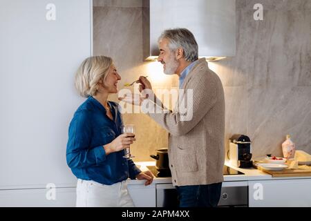 Joyeux couple d'âge mûr préparant le dîner dans la cuisine à la maison Banque D'Images