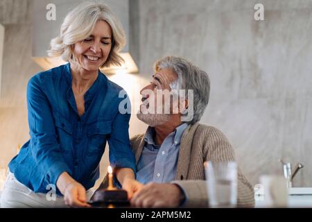 Couple d'âge mûr célébrant l'anniversaire avec gâteau dans la cuisine à la maison Banque D'Images