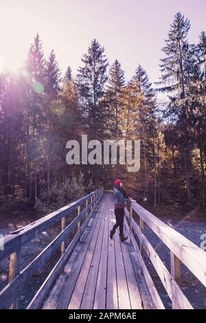 Femme portant un chapeau en laine rouge et une veste denim sur un pont en automne Banque D'Images