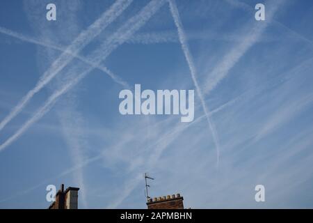 Le ciel bleu et les brumes éphémères blanches des pistes de vapeur traversent le ciel de Paris encadrés par l'indice d'une cheminée parisienne et d'une antenne tv Banque D'Images